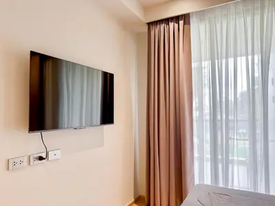 a bedroom with a flat screen tv and a window at Laguna BeachSide Apartment in Bang Tao Beach