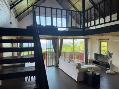 a living room with a white couch and a balcony at Choncharm house 2 in Kata Beach