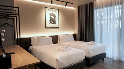 a hotel room with two beds and a window at Lush inn Phuket in Ban Suan