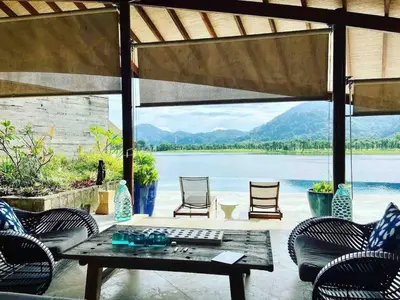 a patio with a table and chairs and a view of the water at Tranquil lake view villa on Phuket golf estate in Kathu