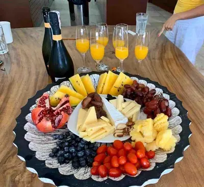 a plate of cheese and fruit on a table with glasses of wine at Tranquil lake view villa on Phuket golf estate in Kathu