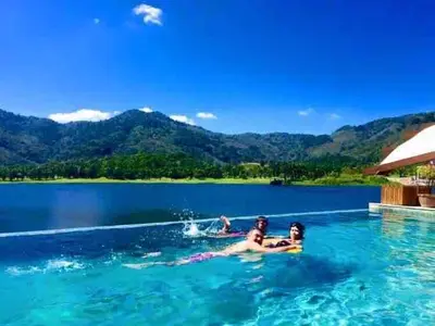 a group of people swimming in a pool in the water at Tranquil lake view villa on Phuket golf estate in Kathu