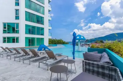 a pool with chairs and tables next to a building at Studio Sea view with kitchen by Renttini in Kamala Beach
