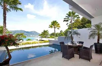 a patio with a table and chairs and a swimming pool at Atika Villas xero oceanfront pool villa in Patong Beach