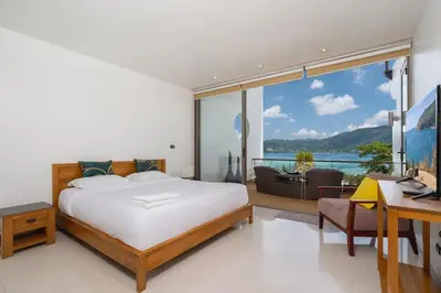 a bedroom with a bed and a desk and a window at Atika Villas xero oceanfront pool villa in Patong Beach