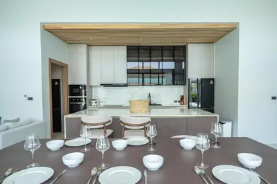 a kitchen with a table with plates and wine glasses at Mouana Breeze Mai Khao VIP 4-bedroom Pool Villa 9913 in Mai Khao Beach