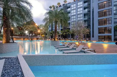 a pool with lounge chairs and palm trees and buildings at Kamala Suite CTG L202, Top Amenities near Cafe del Mar and Fantasea in Kamala Beach