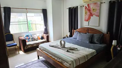 a bedroom with a bed and a chair and a window at Rawai Naiharn 3 bedroom house in Rawai Beach