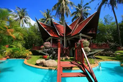 a resort with a swimming pool and a house at Coco palace resort in Rawai Beach