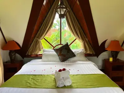 a bedroom with a bed with two towels and a window at Coco palace resort in Rawai Beach