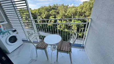 a balcony with a table and chairs and a washing machine at Phuket apartment in Nai Yang Beach