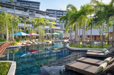 a swimming pool with chairs and palm trees in front of a building at Seaview, cozy apartment, Surin in Surin Beach