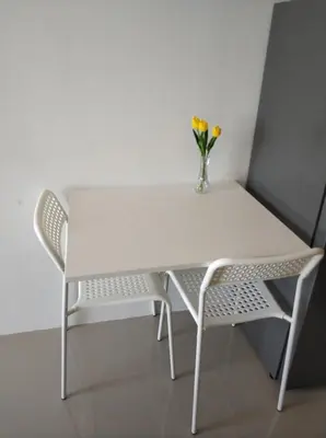 a white table and two chairs with a vase of flowers at Lovely Mai Khao studio room in Mai Khao Beach