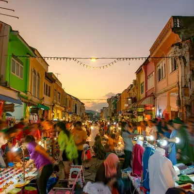 a crowd of people at an outdoor market at dusk at Serene Panwa beachfront in Ban Ao Makham