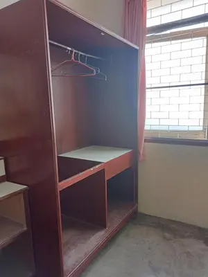 an empty closet with a wooden cabinet in a room at Suksabai Hotel Phuket in Phuket Town