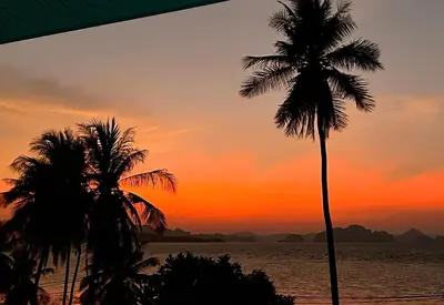 two palm trees on the beach at sunset at Villa Miyoko Ko Yao Noi Enjoy nature's beauty and stunning sunsets in Ko Yao Noi