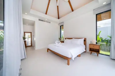 a bedroom with a bed and a large window at Anchan Villas Phuket - 4 BR Signature Pool Villa by Escape Villas in Ban Phru Champa