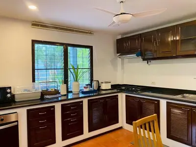 a kitchen with wooden cabinets and a ceiling fan at Cozy Space Kamala in Kamala Beach