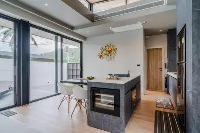 a kitchen with a fireplace and a dining area with chairs at Pangolin villa Nai Thon Beach in Nai Thon Beach