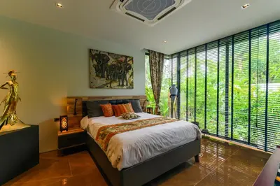 a bedroom with a large bed and large windows at Botanica Modern Loft by RESAVA in Bang Tao Beach