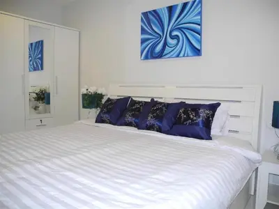 a white bed with blue pillows on top of it at 2 Bedrooms Beachfront Apartment in Patong in Patong Beach
