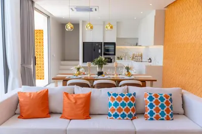 a living room with a white couch with orange pillows at Coconus Pool Villa \u963f\u4e3d\u838e \u6cf3\u6c60\u522b\u5885 in Ban Pak Lak