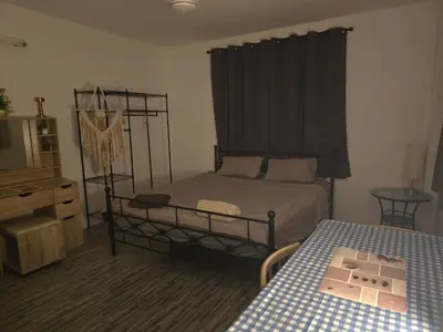 a bedroom with a bed and a table and a television at Kata Cozy Guest Room in Kata Beach