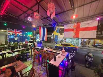a woman sitting at a table in a restaurant with flags at Kata Cozy Guest Room in Kata Beach