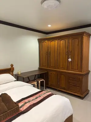 a bedroom with a bed and a desk and wooden cabinets at Spacious and cozy Thai House in Ban Bang Khu