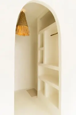 a chandelier hangs over a white room with shelves at The hidden home in Patong Beach