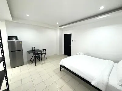 a bedroom with a bed and a table and a refrigerator at Patong Canal Villa 110 in Patong Beach