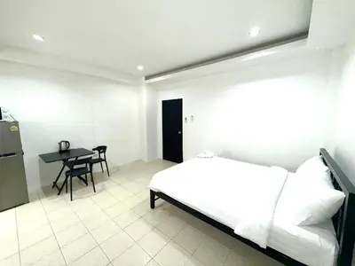 a white room with a bed and a table at Patong Canal Villa 110 in Patong Beach