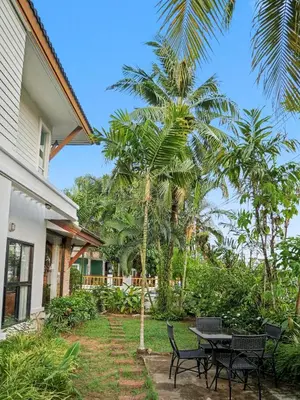 a patio with a table and chairs and palm trees at 3 Bedrooms - 2 floor with garden in Prime Location in Thalang