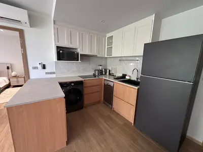 a kitchen with a black refrigerator and wooden cabinets at 2 bdr Apartments Laguna Beachside 50m from Bangtao Beach in Bang Tao Beach