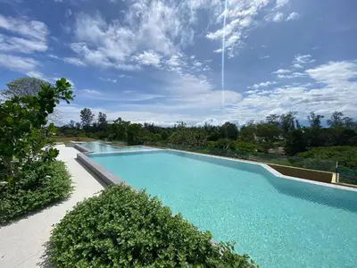 a large swimming pool with blue water and trees at 2 bdr Apartments Laguna Beachside 50m from Bangtao Beach in Bang Tao Beach