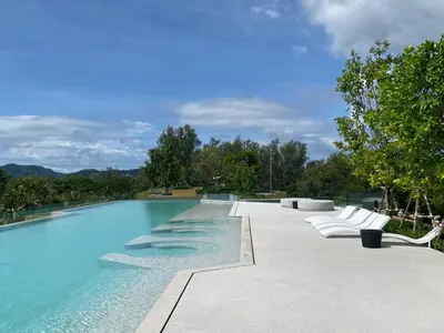 a swimming pool with white lounge chairs and trees at 1 bdr Mountain View Apartment 50 m from Bangtao Beach in Bang Tao Beach