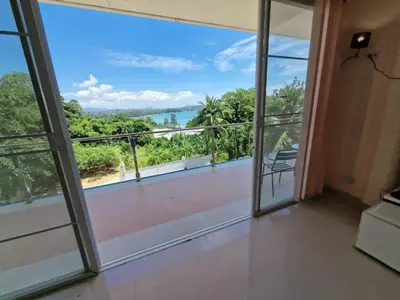 a room with a balcony with a view of the ocean at Phuket Arkadia Home in Nai Harn Beach
