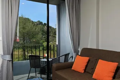 a living room with a couch and a view of a balcony at 6th avenue surin in Surin Beach