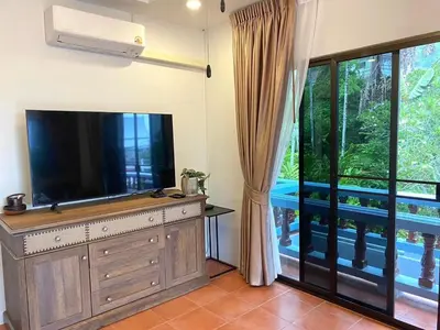 a living room with a flat screen tv and a window at The Vintage Kamala in Kamala Beach