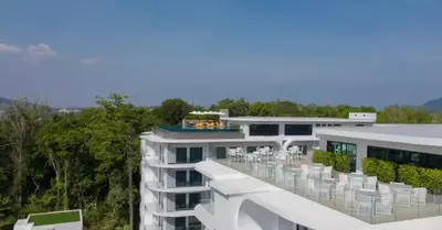 a white building with chairs on the balcony at Utopia Phuket Naiharn Beach Grand Resort & Spa in Rawai Beach