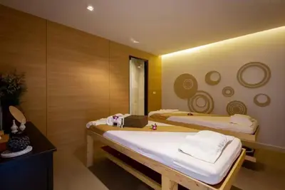 a bedroom with two beds and a mirror at Utopia Phuket Naiharn Beach Grand Resort & Spa in Rawai Beach