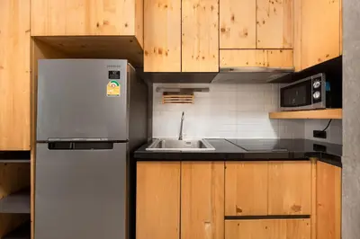 a kitchen with a stainless steel refrigerator and wooden cabinets at Relife Sol 2 min to Nai Harn beach by TropicLook in Rawai Beach