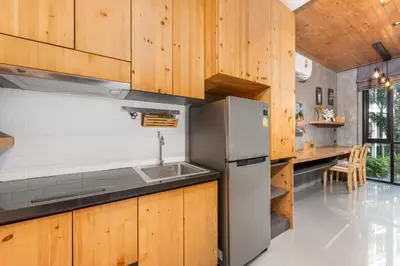 a kitchen with wooden cabinets and a stainless steel refrigerator at Relife Zen 2 min to Nai Harn beach in Rawai Beach
