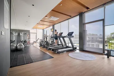 a gym with a woman exercising on treadmills at Stylish Beachfront Two-Bedroom Flat in Nai Thon Beach