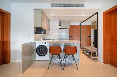a kitchen with a washing machine and two chairs at Stunning Lake View One Bedroom in Laguna Phuket