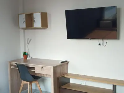 a desk with a chair and a tv on a wall at Sila Apartment in Ban Thalat Choeng Thale