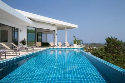 a swimming pool with chairs and a house at Serenity Villa in Bang Tao Beach