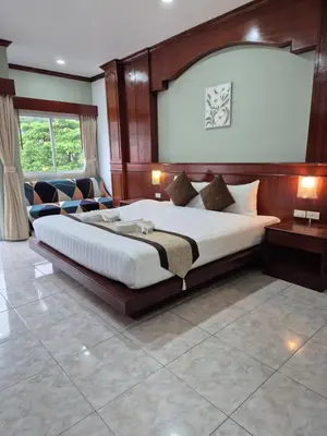 a bedroom with a large bed with a wooden headboard at New Forest Patong Hotel, Patong Beach in Patong Beach
