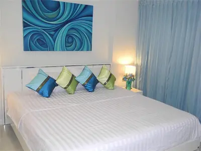 a bedroom with a bed with blue and green pillows at Ideally Apartment close to Kata Beach in Kata Beach