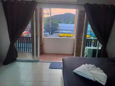 a room with a door open to a balcony with a view at the three pyramids in Rawai Beach